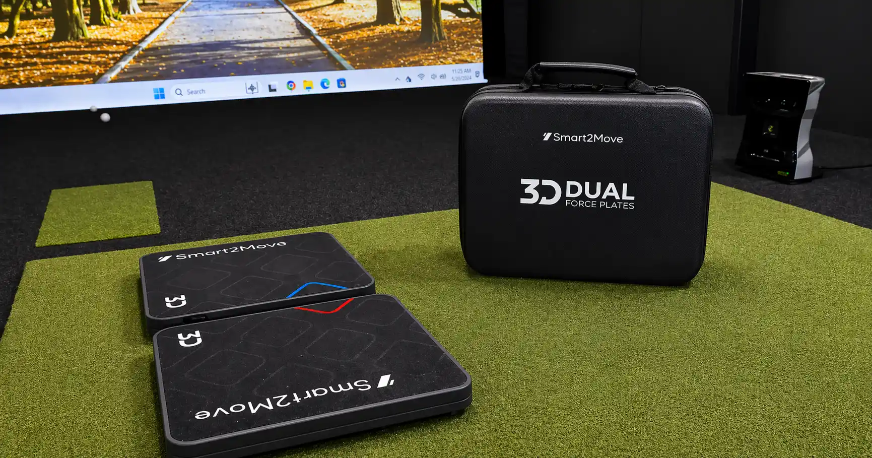 Smart2Move 3D Dual Force Plates on a green turf mat next to their carrying case in a golf simulator room.