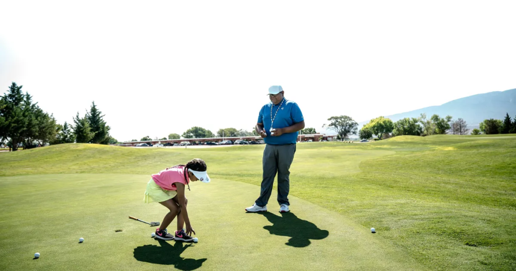 Child practicing golf with instructor